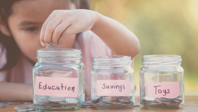 Young girl putting money into savings jars