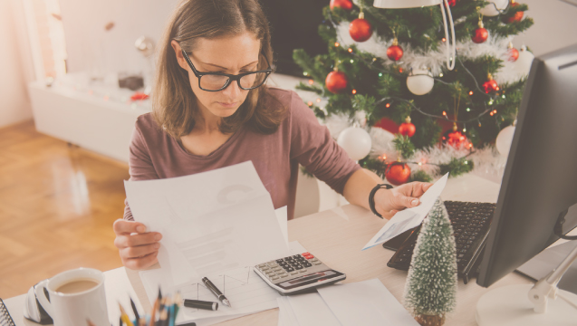 woman doing taxes in front of a Christmas tree