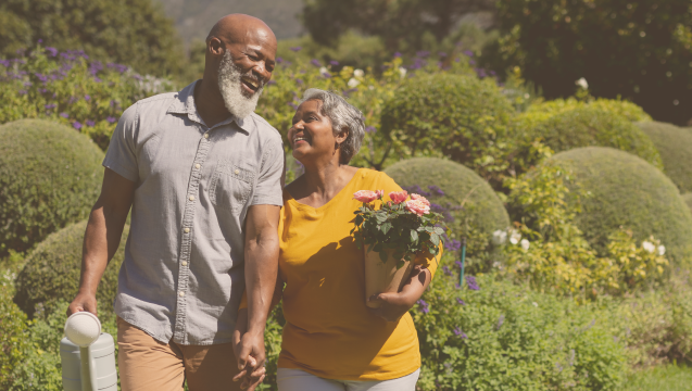 a happy retired couple is walking in their garden