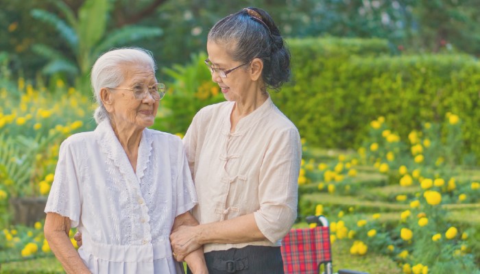 Elderly women being aided by her grown daughter