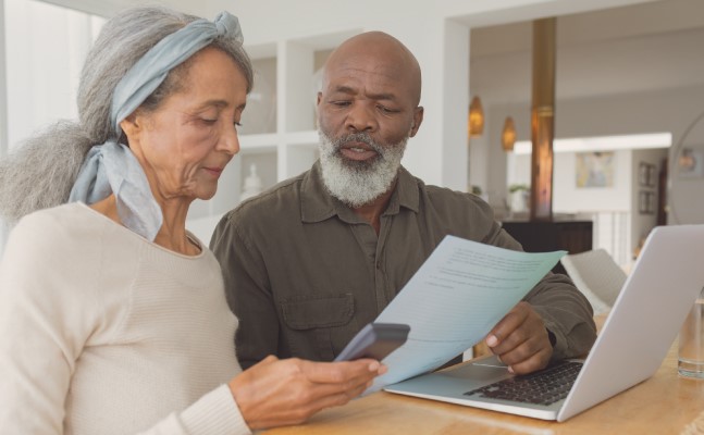 African American elderly couple looking at computer and papers